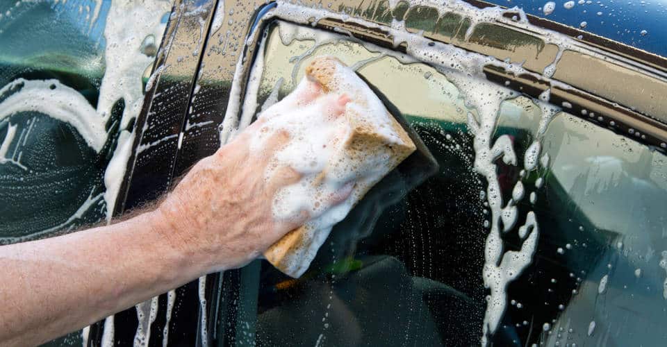 hand holding soapy sponge washing car 1