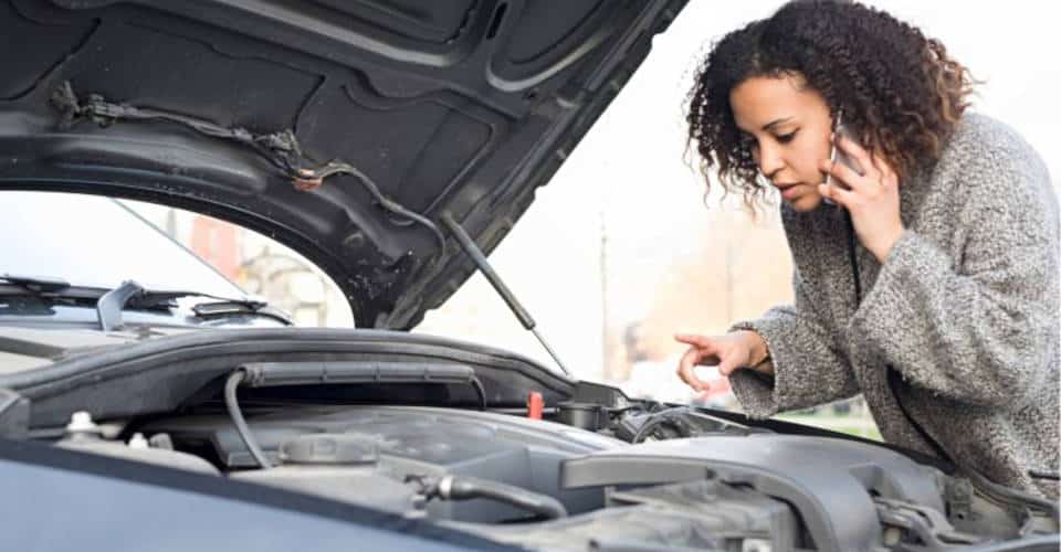 woman on phone opens car hood to look at engine 1